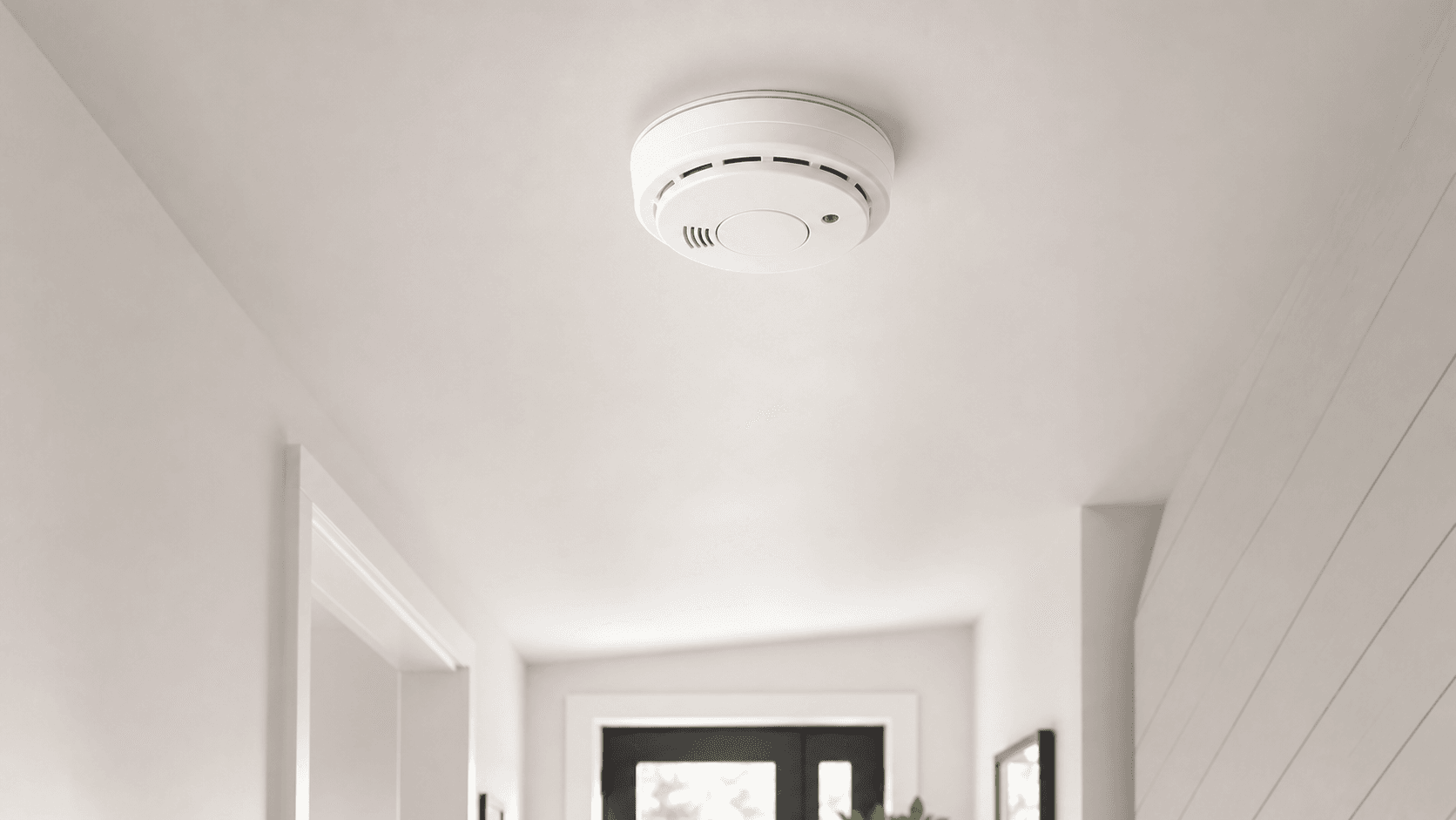Detecteur de fumee connecte installe au plafond d'un couloir lumineux
